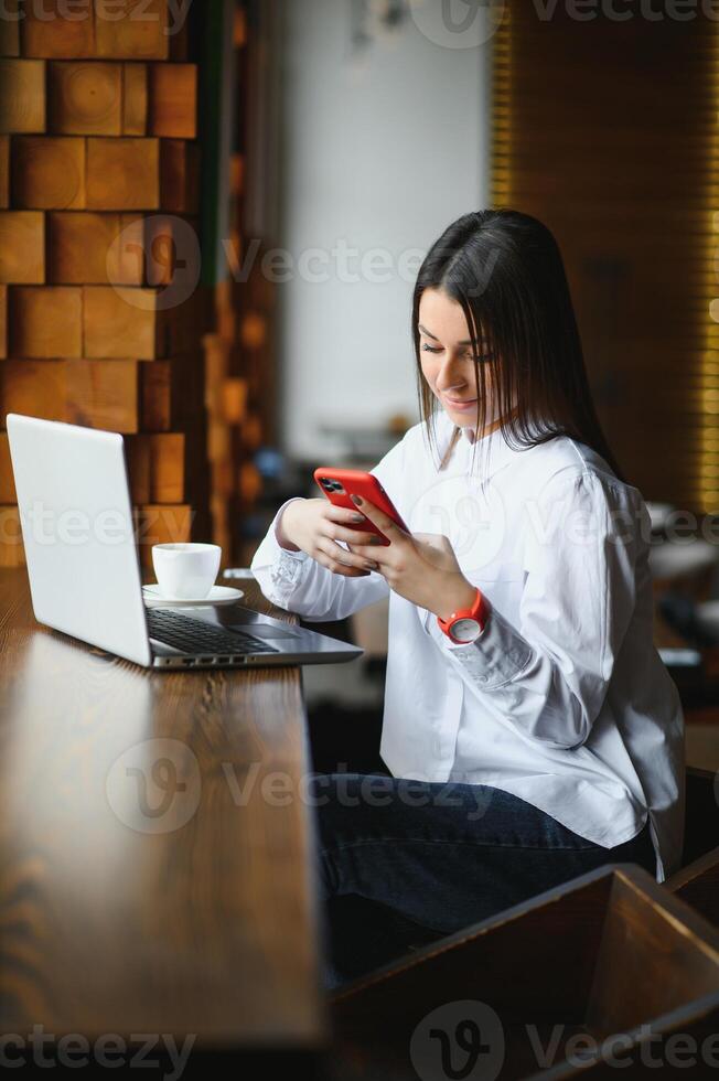 fiducioso attività commerciale donna ricerca curriculum vitae su luogo attraverso il computer portatile computer mentre seduta nel ristorante durante opera rompere. femmina progetto manager utilizzando applicazioni su taccuino dispositivo, riposo nel bar foto