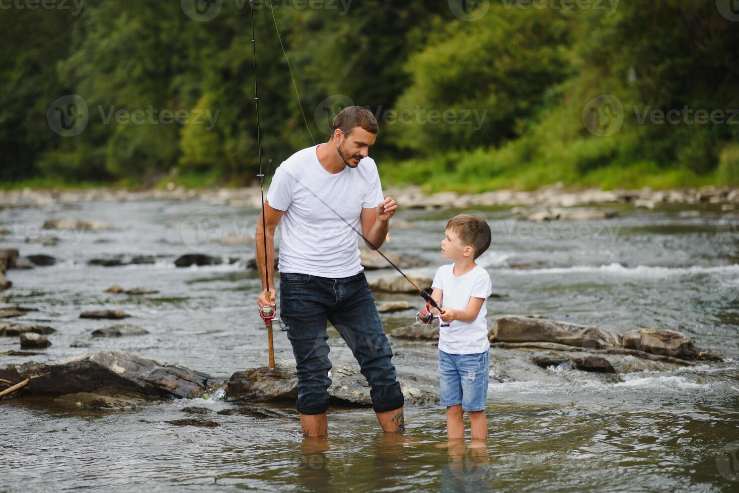 un' padre insegnamento il suo figlio Come per pesce su un' fiume al di fuori nel estate luce del sole foto