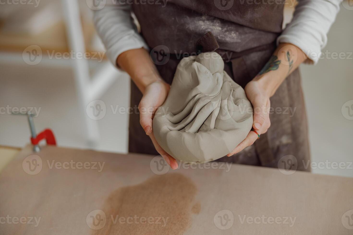 vicino su di donna preparazione argilla per creare un' boccale su un' di legno tavolo nel ceramica studio foto