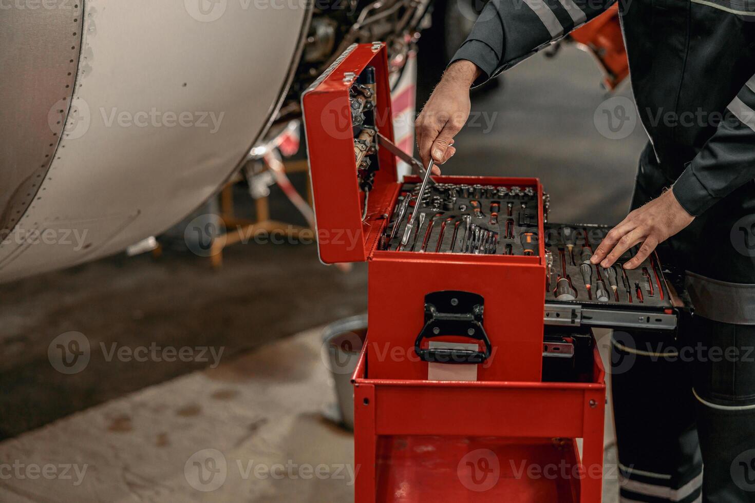 maschio meccanico utilizzando strumento scatola nel hangar foto