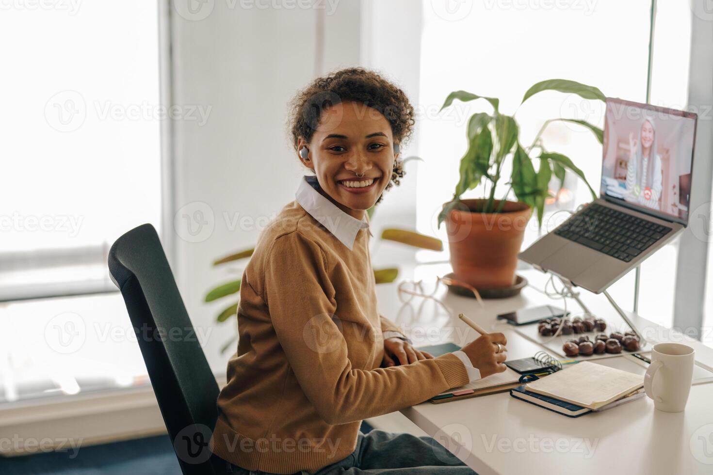 femmina libero professionista avere video conferenza con cliente e fabbricazione Appunti seduta nel accogliente coworking foto