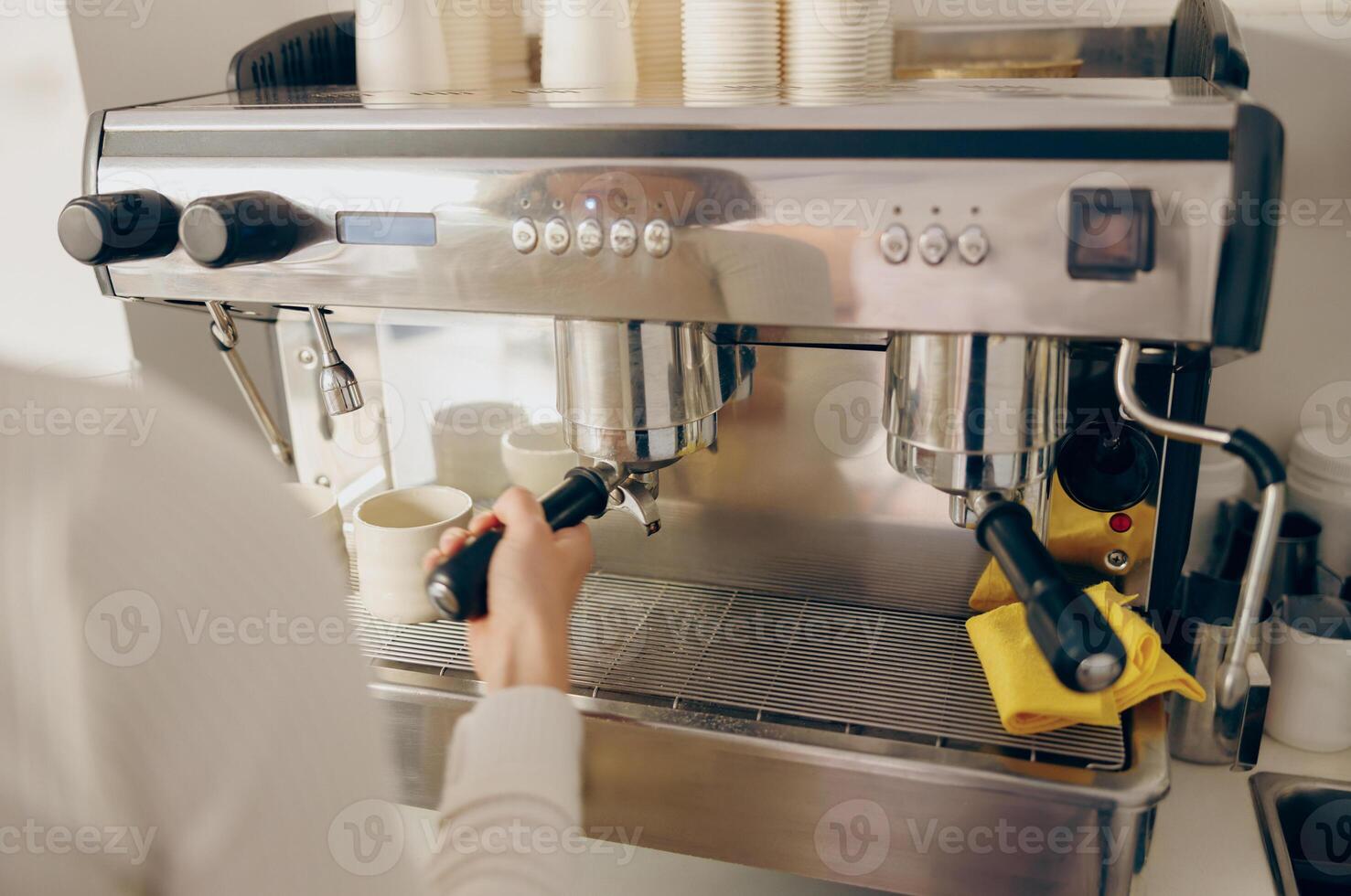 vicino su di femmina barista fabbricazione caffè nel un' caffè macchina mentre Lavorando nel bar foto