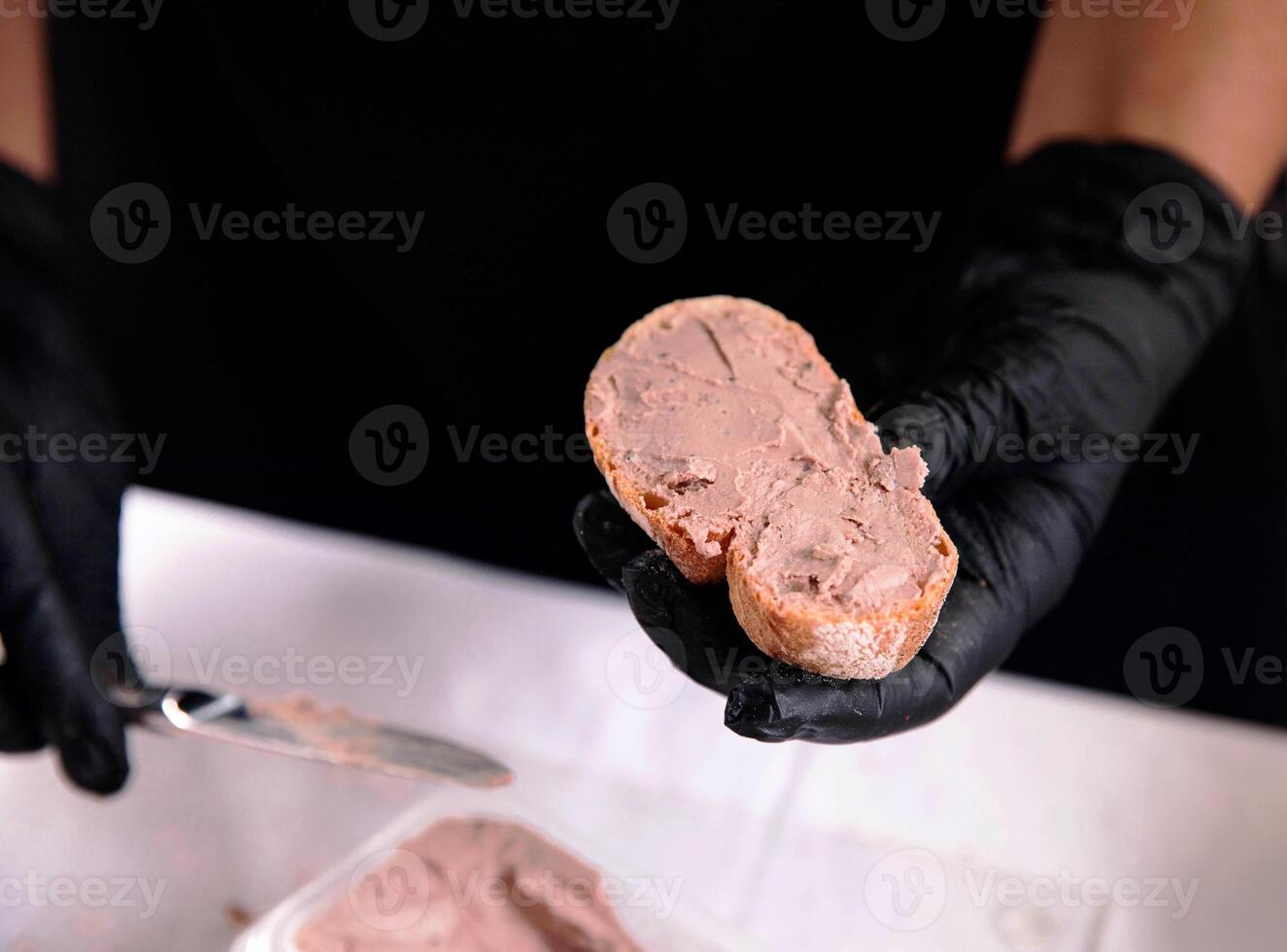 mani con guanti diffusione paté su tostato pane fette nel ristorante foto