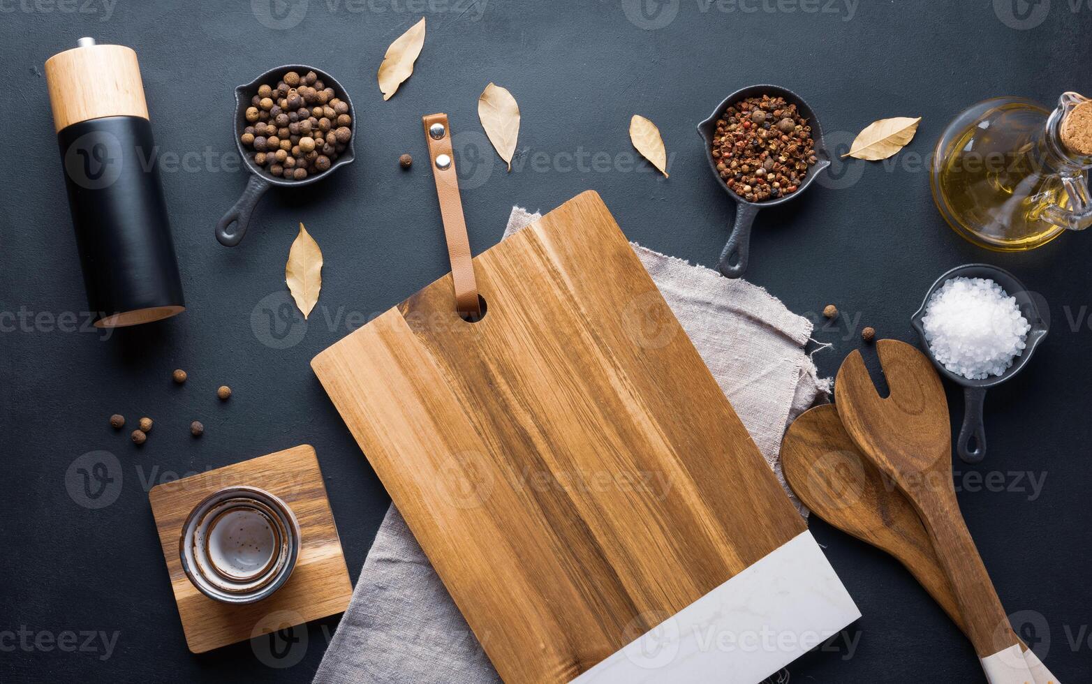 vuoto di legno taglio asse, sale, Pepe di Giamaica, grani di pepe e oliva olio nel un' bottiglia su un' nero tavolo foto