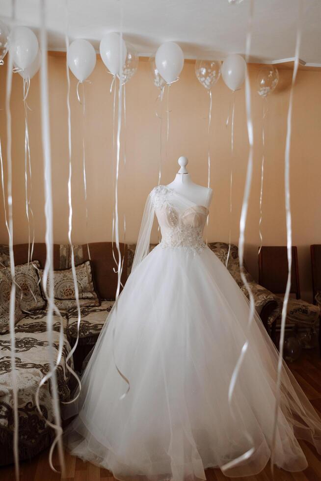 Camera da letto interno con nozze vestito preparato per il cerimonia. un' bellissimo lussureggiante nozze vestito su un' indossatrice nel un' Hotel camera. foto