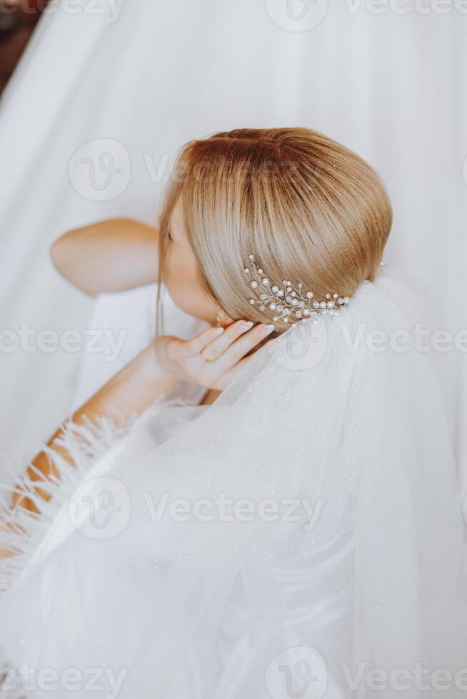 avvicinamento biondo sposa con moda nozze acconciatura e trucco. un' giovanile sposa con un' sofisticato bridal pettinatura in casa di un' finestra foto