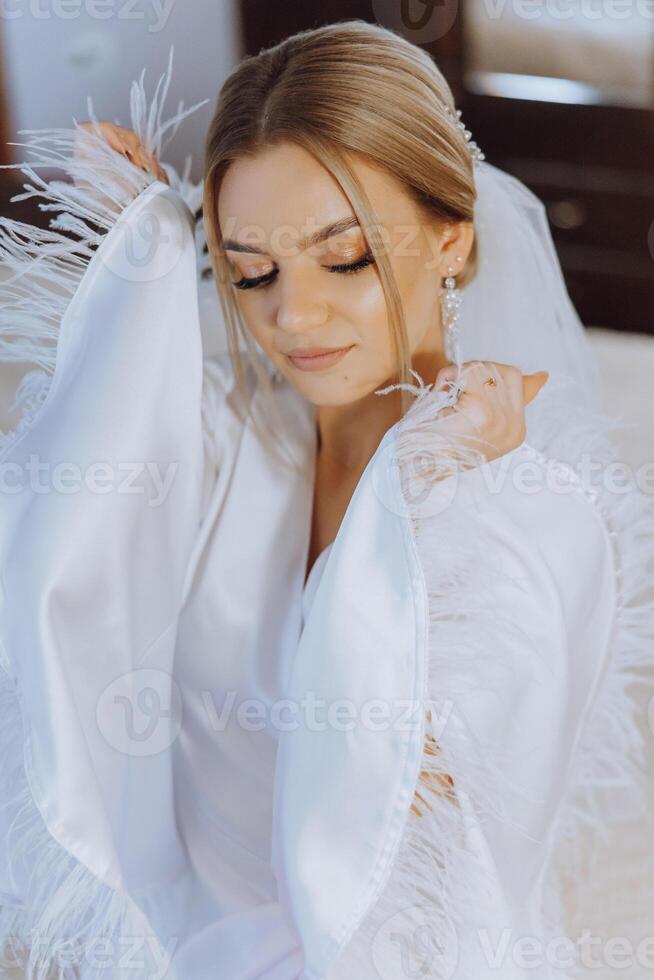 avvicinamento biondo sposa con moda nozze acconciatura e trucco. un' giovanile sposa con un' sofisticato bridal pettinatura in casa di un' finestra foto