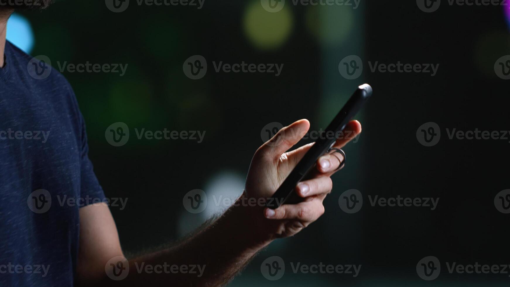 moderno persona su smartphone durante passeggiare in ritardo a notte, guardare in giro città centro con illuminato grattacieli. casuale uomo sms su Telefono e a piedi centro. palmare sparo. vicino su. foto