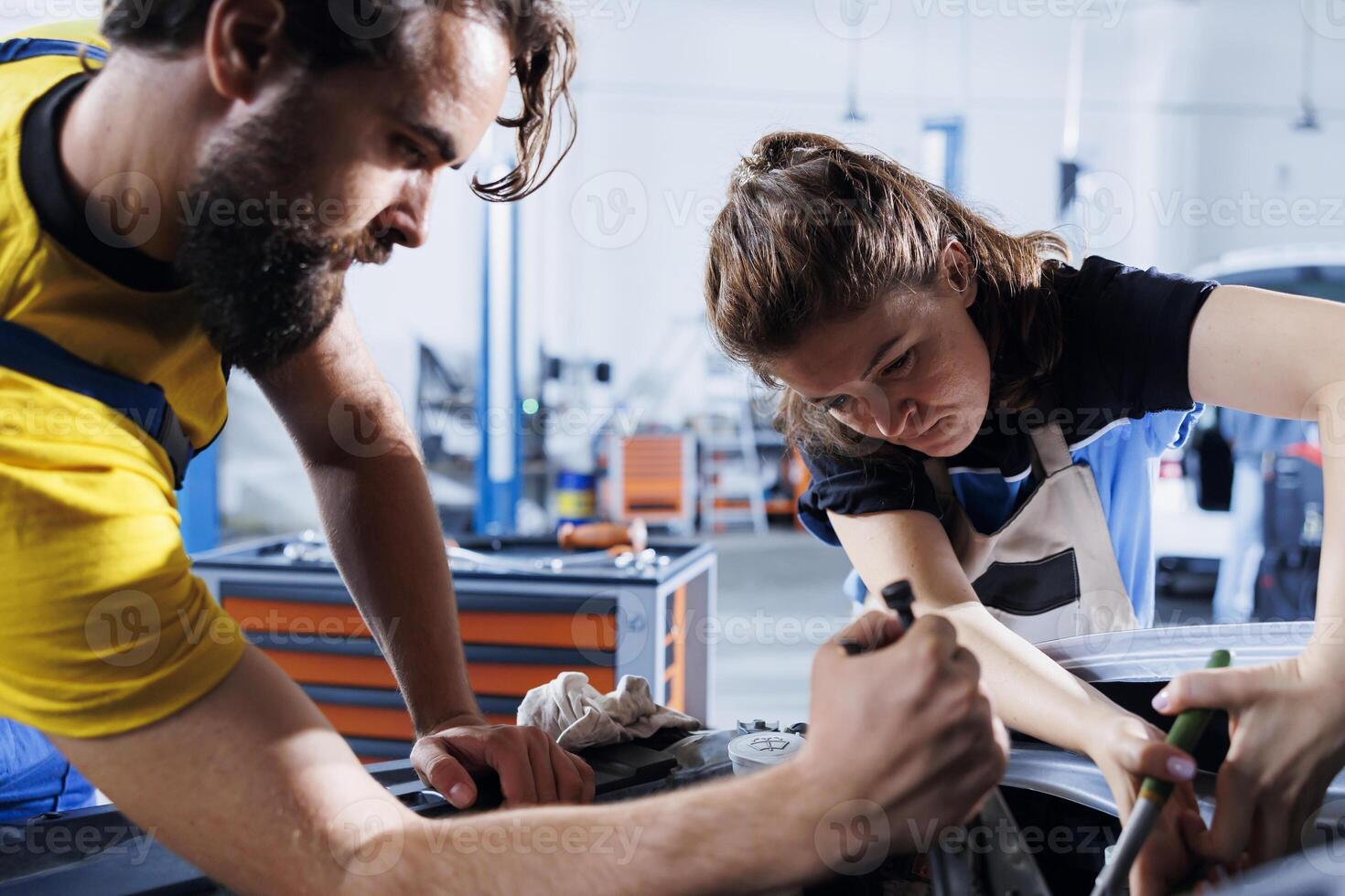 esperto riparatori nel auto riparazione negozio Lavorando insieme su fissaggio macchina, discutere migliore opzioni. lavoro di gruppo dipendenti collaboratore su manutenzione rotto veicolo, controllo per difettoso batteria foto