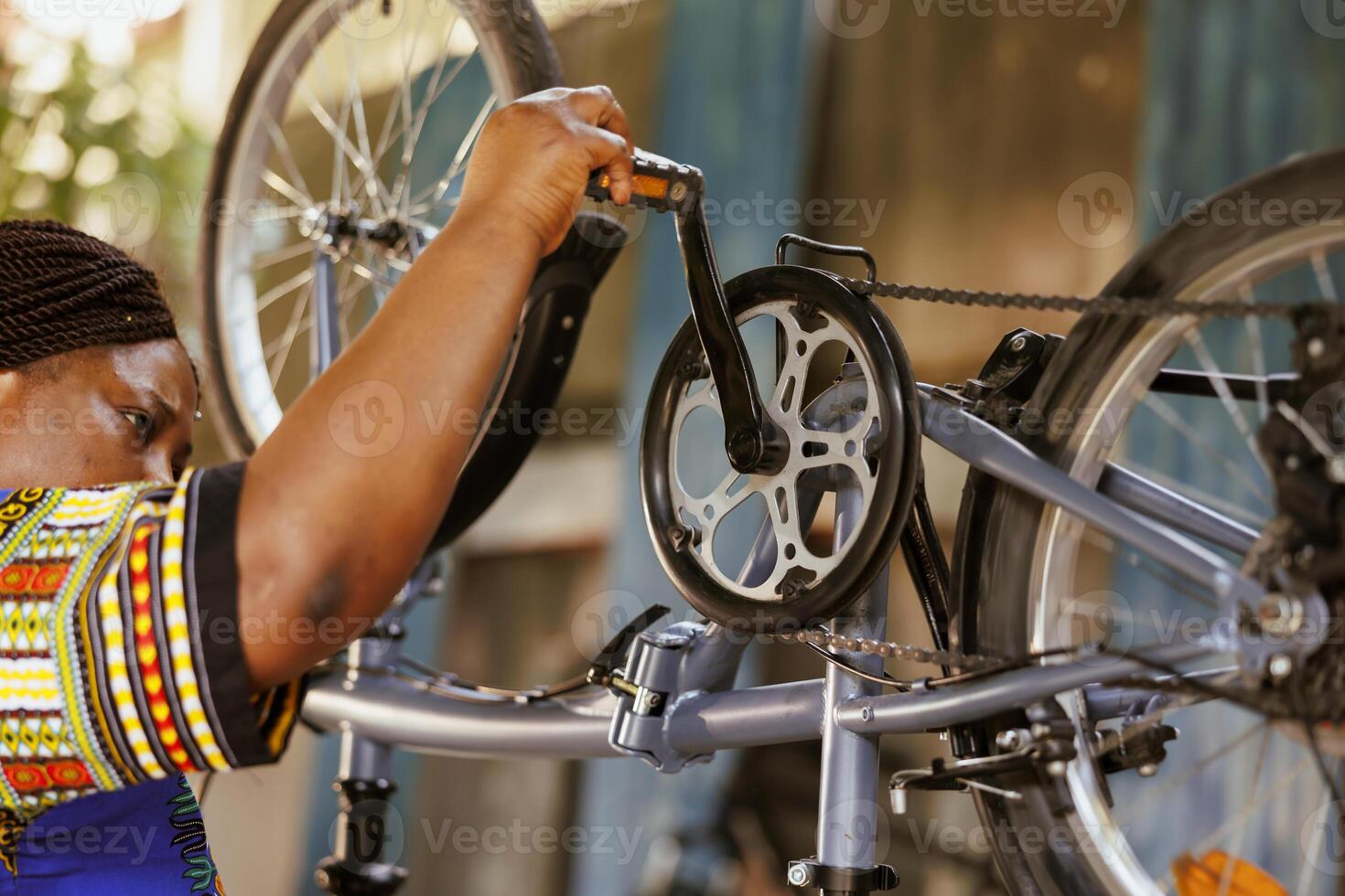 appassionato amante dello sport nero donna diligentemente ispezionando e riparazione bicicletta pedali e Catene. attivo africano americano femmina ciclista fabbricazione annuale aggiustamenti per moderno bicicletta. foto