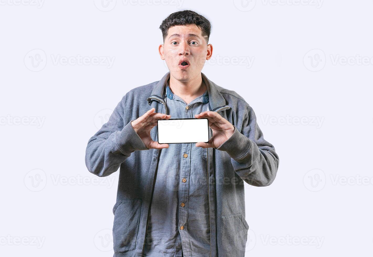 sorpreso tipo mostrando cellula Telefono schermo isolato. stupito giovane uomo mostrando un annuncio pubblicitario su schermo cellula Telefono foto
