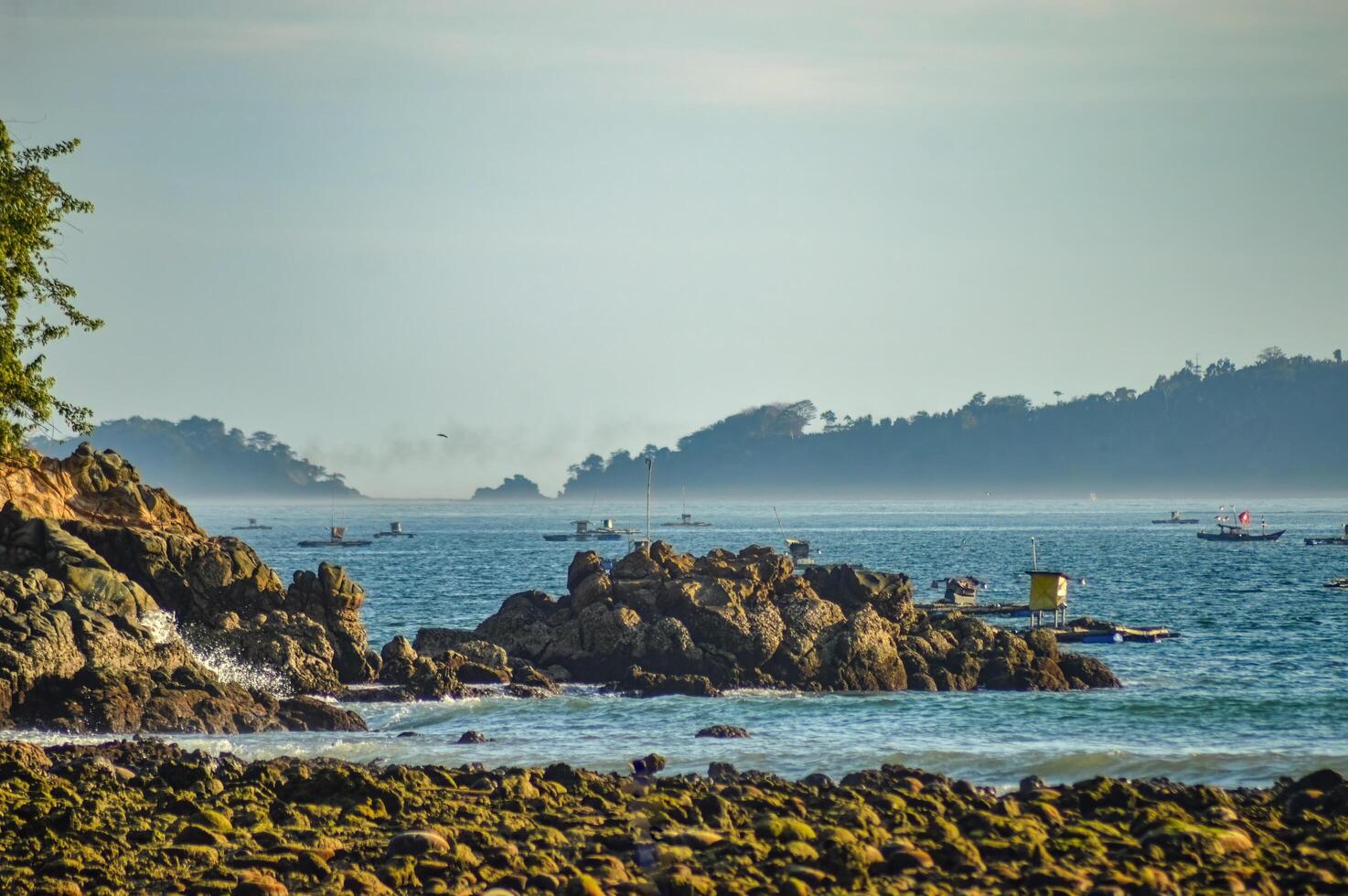 corallo roccioso spiaggia con mare sfondo con isole foto