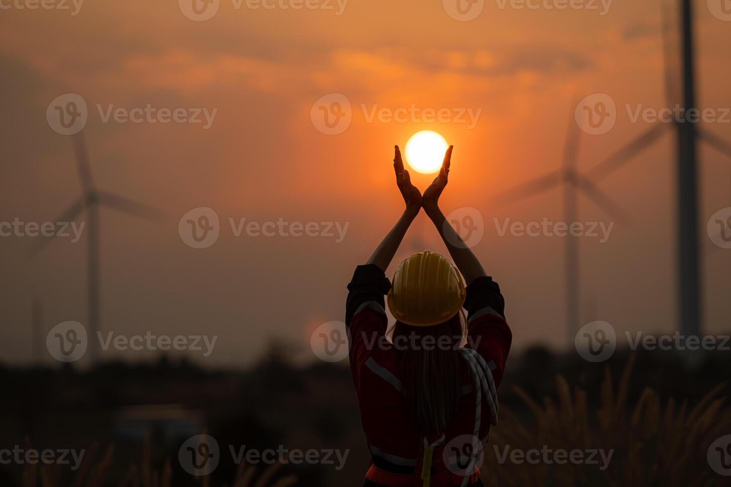 ingegnere donna con giallo casco e vento turbina su tramonto sfondo. foto