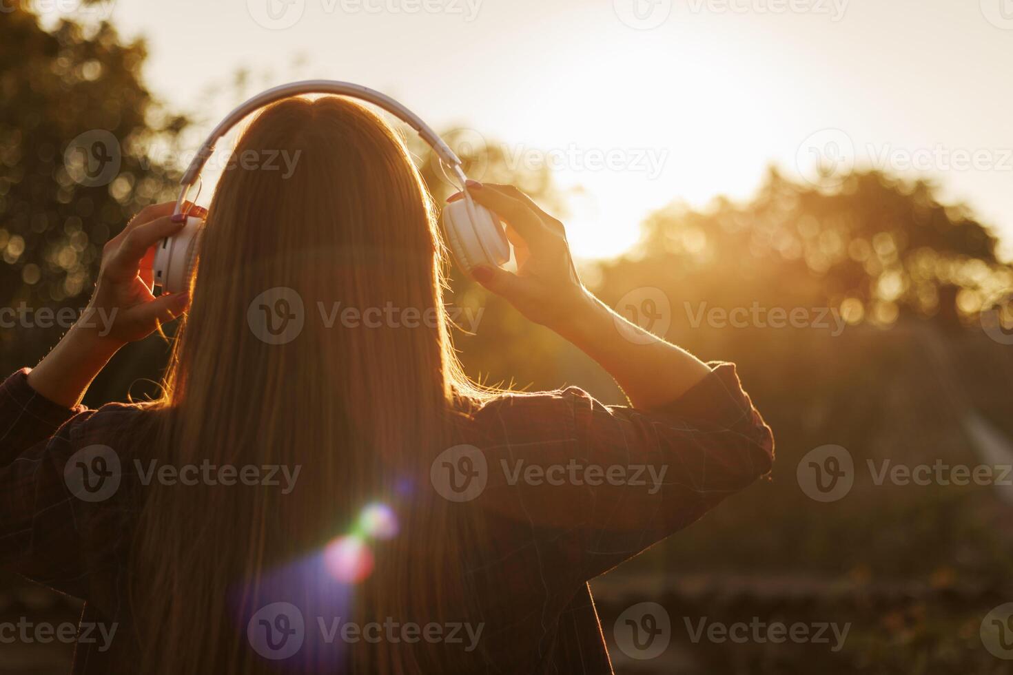 giovane donna nel cuffie ascoltando per musica a tramonto foto