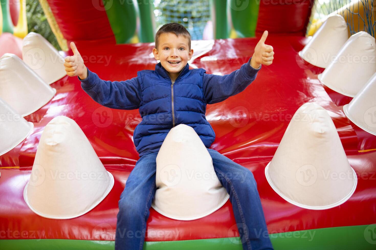 contento ragazzo avendo un' molte di divertimento su un' colorato gonfiare castello foto