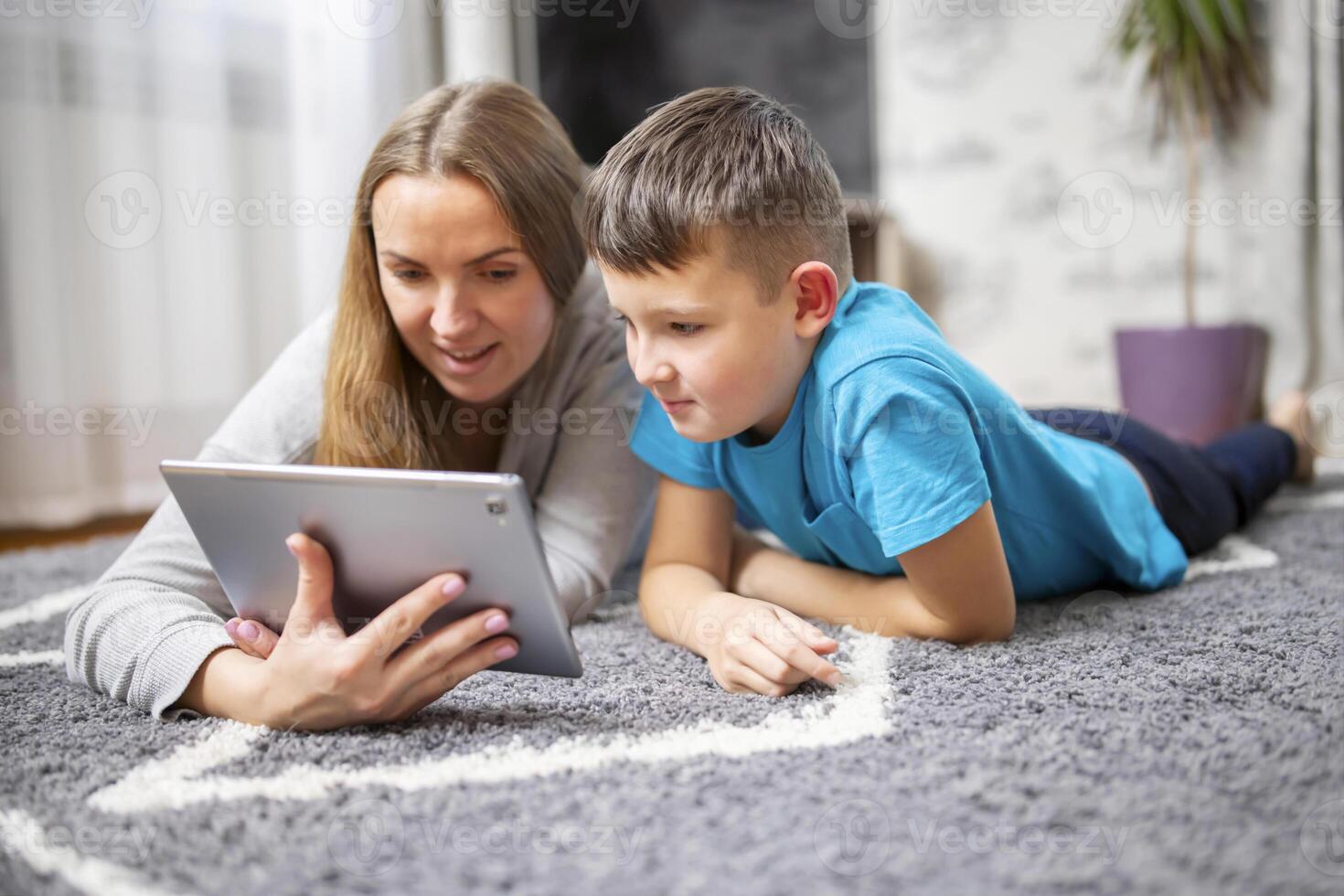 contento amorevole famiglia. giovane madre e sua figlio utilizzando tavoletta dire bugie su tappeto foto