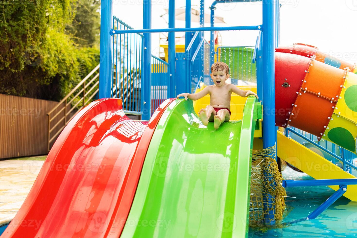 bambino su colorato acqua diapositiva a terreno di gioco. estate divertimento e acqua Giochi concetto. foto