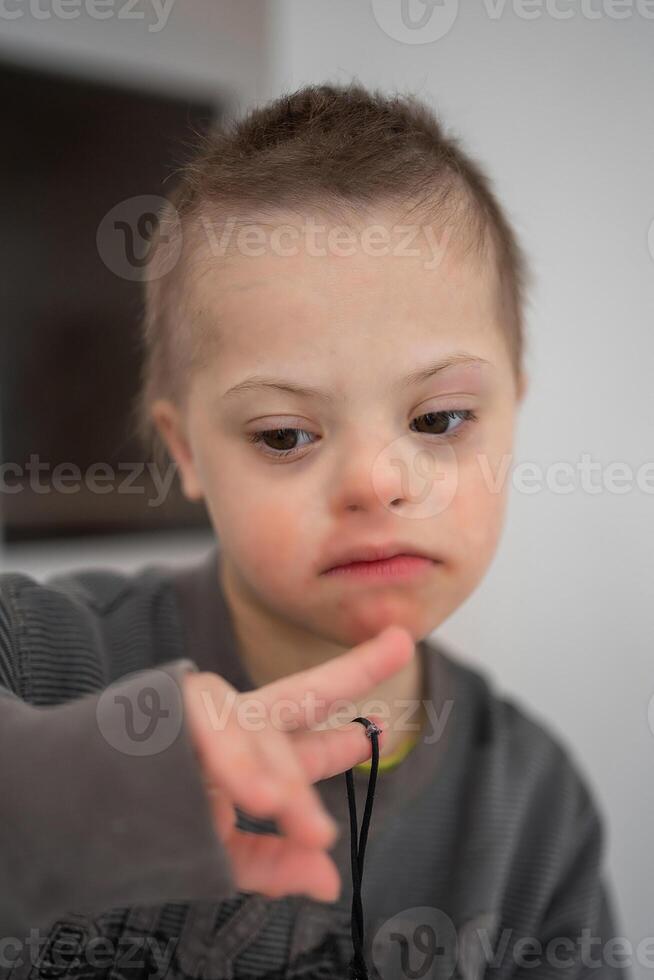 ritratto di piccolo ragazzo con giù sindrome nel casa Camera da letto. alto qualità foto