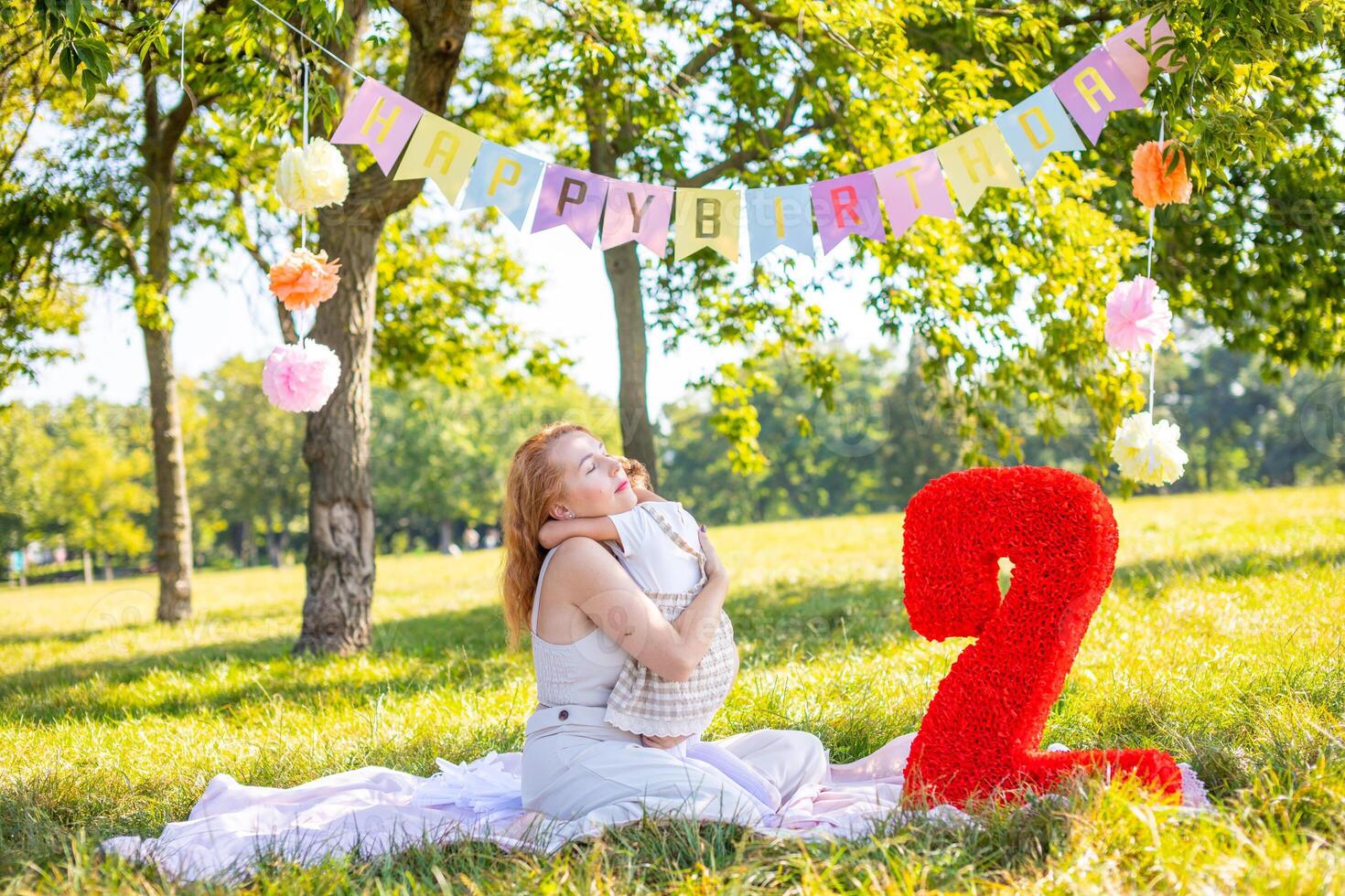 allegro madre e figlia avendo divertimento su bambino compleanno su coperta con carta decorazioni nel il parco foto