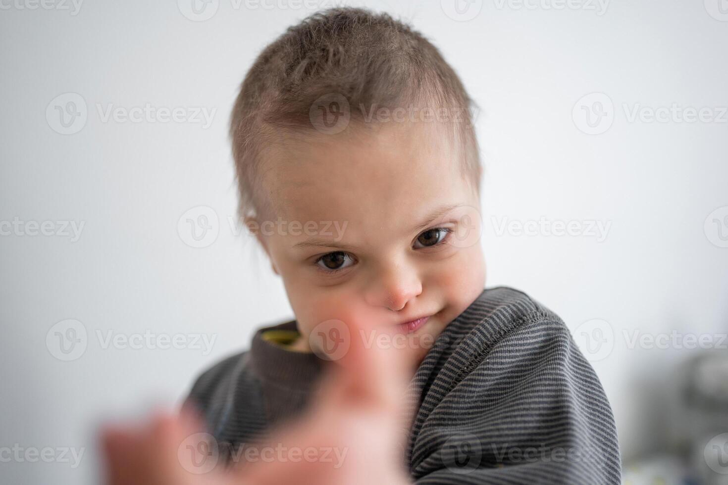 ritratto di piccolo ragazzo con giù sindrome nel casa Camera da letto. alto qualità foto
