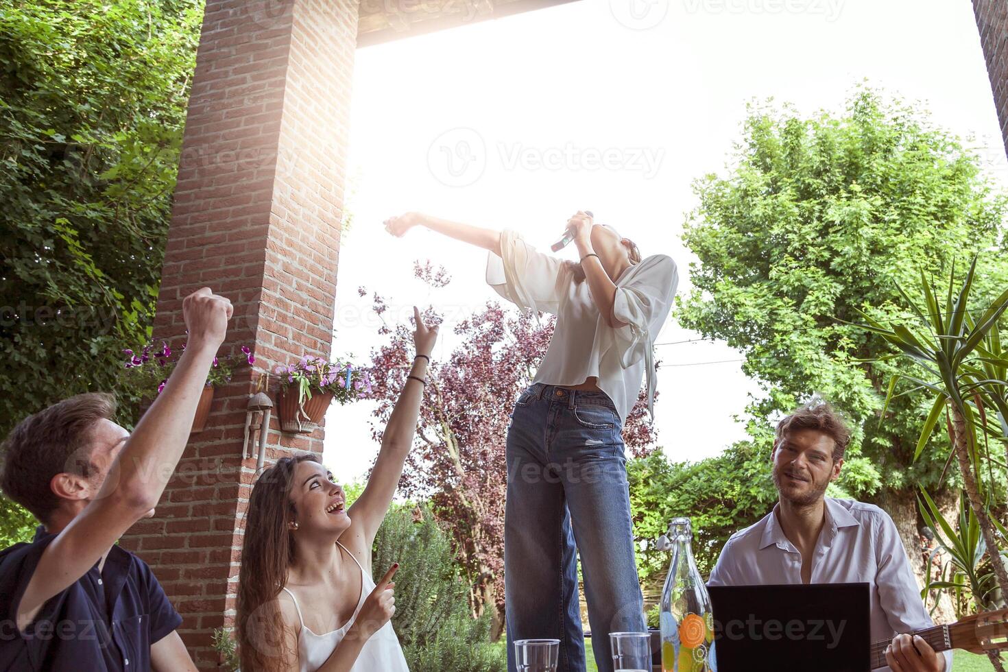 gruppo di giovane amici avendo divertimento cantando un' canzone foto