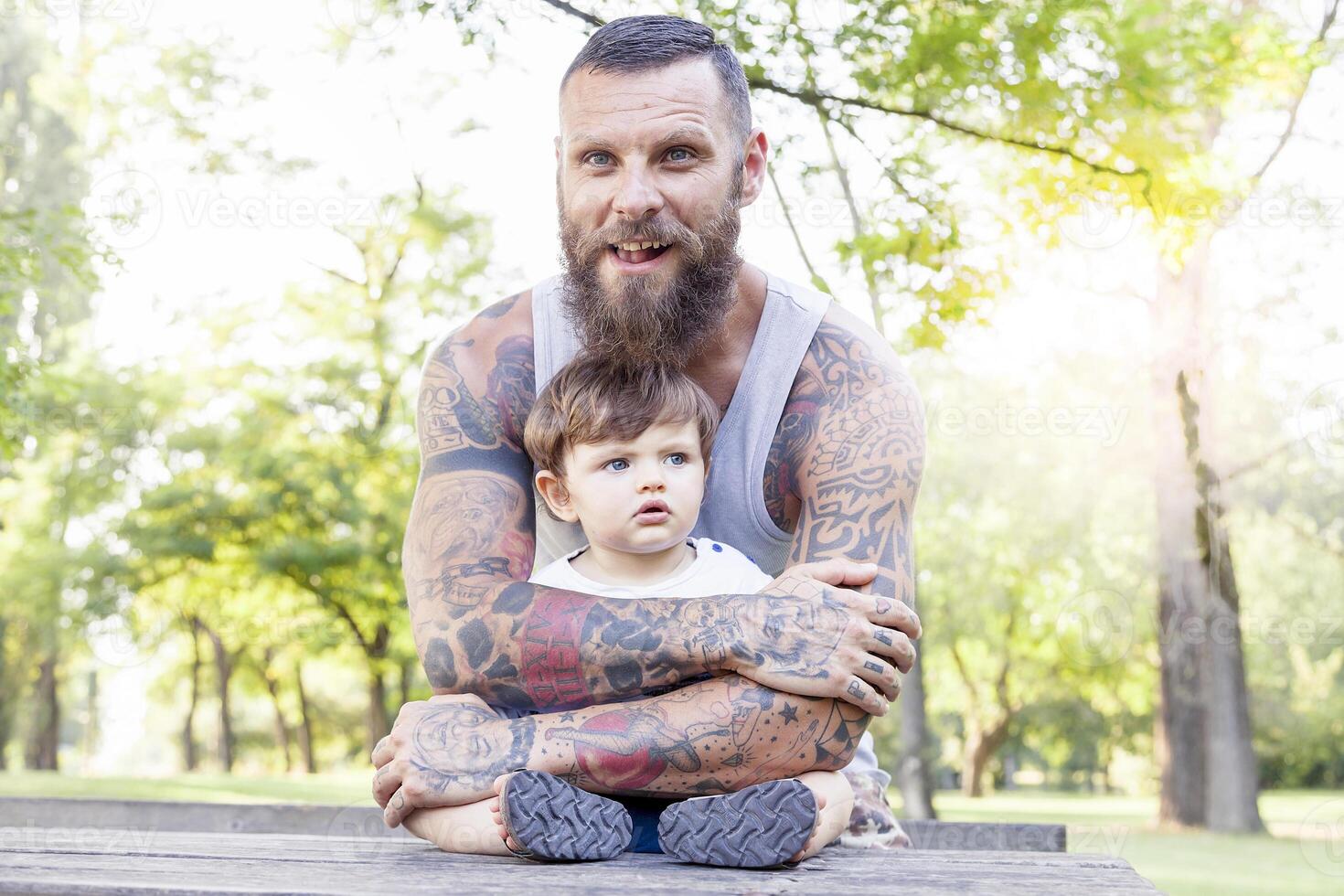 tatuato padre avere divertimento con il suo figlio nel il parco foto