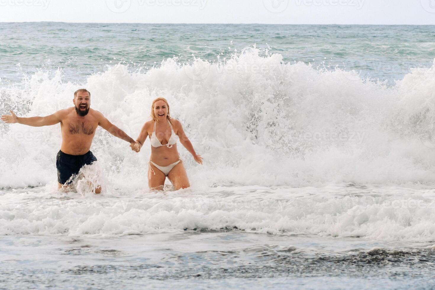 un' sposato coppia nuotate nel il mare su il onde, Tenere mani. il concetto di un' romantico viaggio foto