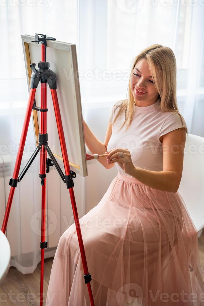 giovane donna artista con tavolozza e spazzola seduta e pittura astratto rosa immagine su tela. arte e creatività concetto foto