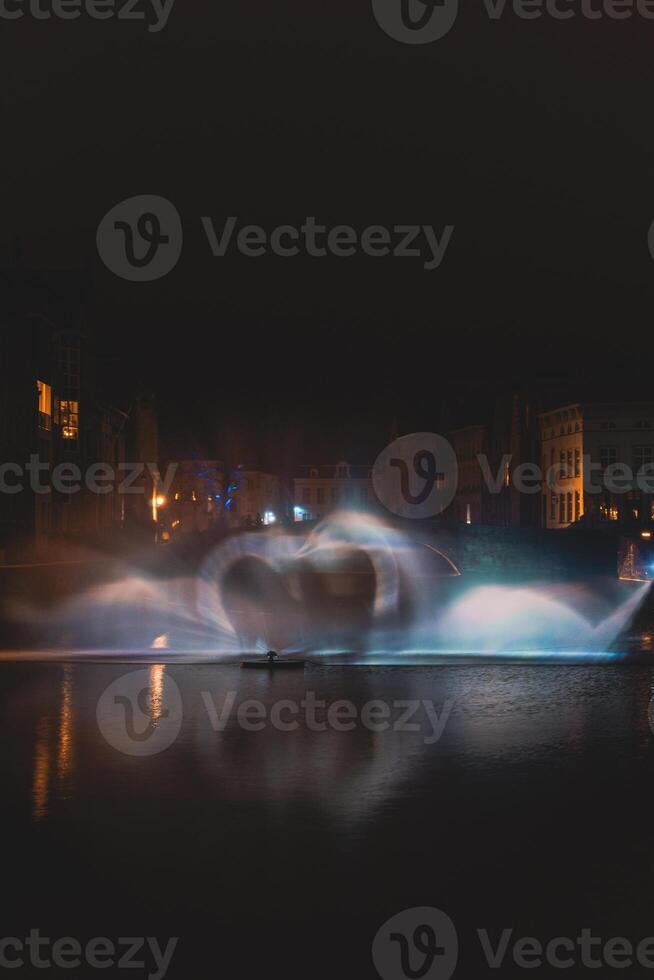 Natale leggero mostrare nel il modulo di il cigno danza su il acqua canale nel il storico quartiere nel Bruges, Belgio. romantico scena foto