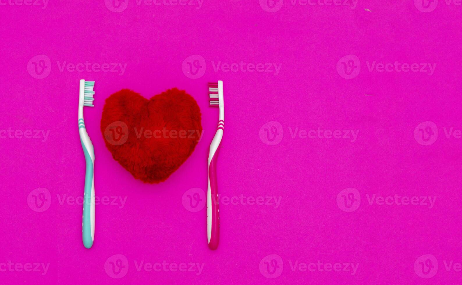 rosso cuore fra Due spazzolini da denti su pastello rosa sfondo. maschio e femmina denti igiene concetto. vicino su. vuoto posto per bello, carino testo, citazione o detti foto