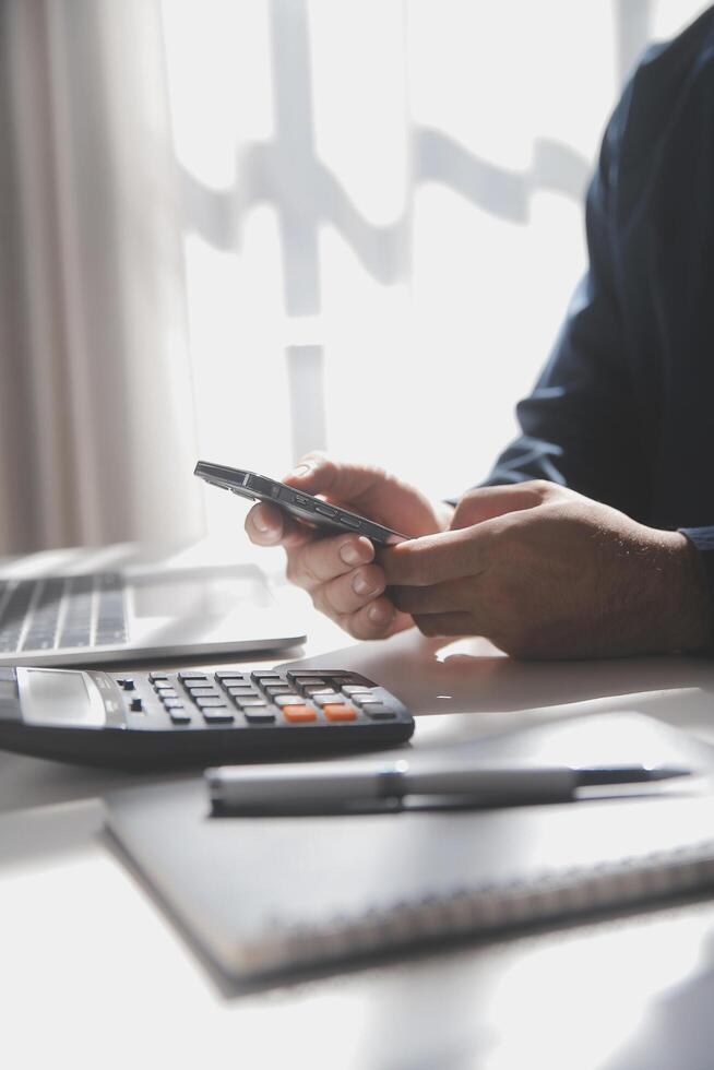 lato Visualizza tiro di un' dell'uomo mani utilizzando inteligente Telefono nel interno, posteriore Visualizza di attività commerciale uomo mani occupato utilizzando cellula Telefono a ufficio scrivania, giovane maschio alunno digitando su Telefono seduta a di legno tavolo, bagliore foto