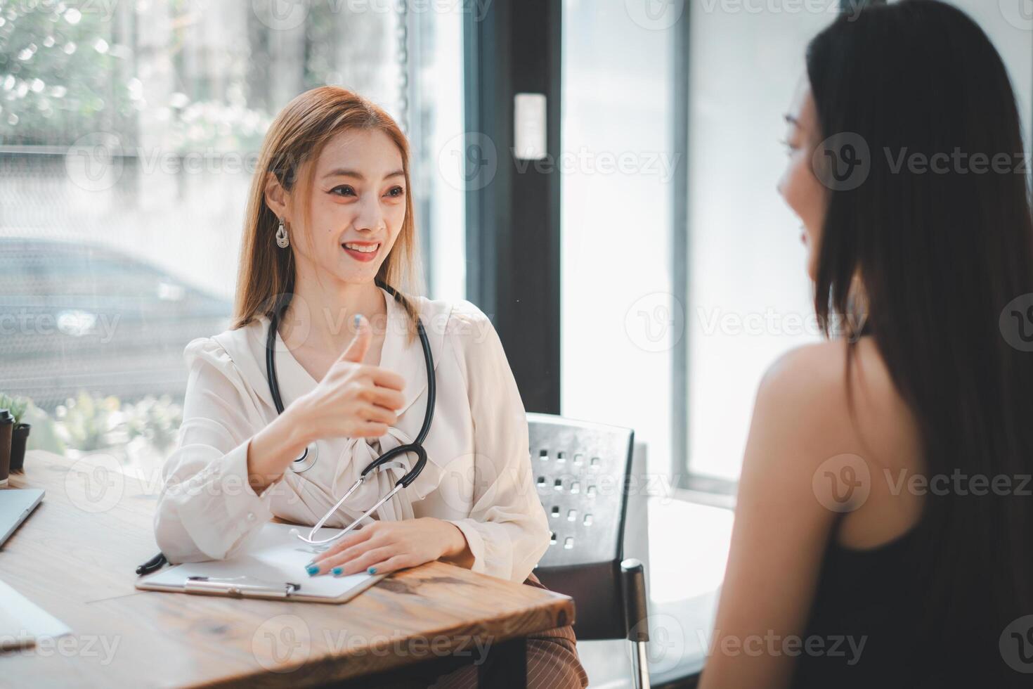 un' sorridente assistenza sanitaria lavoratore dà un' pollice su durante un' positivo consultazione con un' cliente nel un' ben illuminato, moderno ufficio. foto