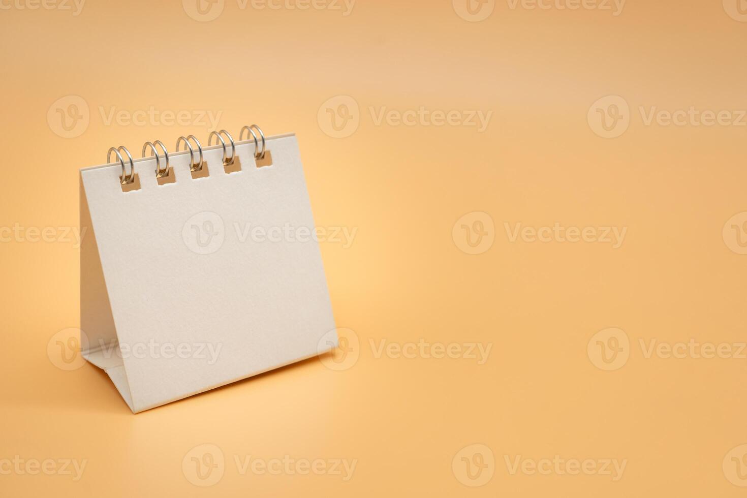 vuoto calendario isolato su arancia sfondo. vuoto carta scrivania spirale calendario. vicino su di un' vuoto riciclare carta modello. foto