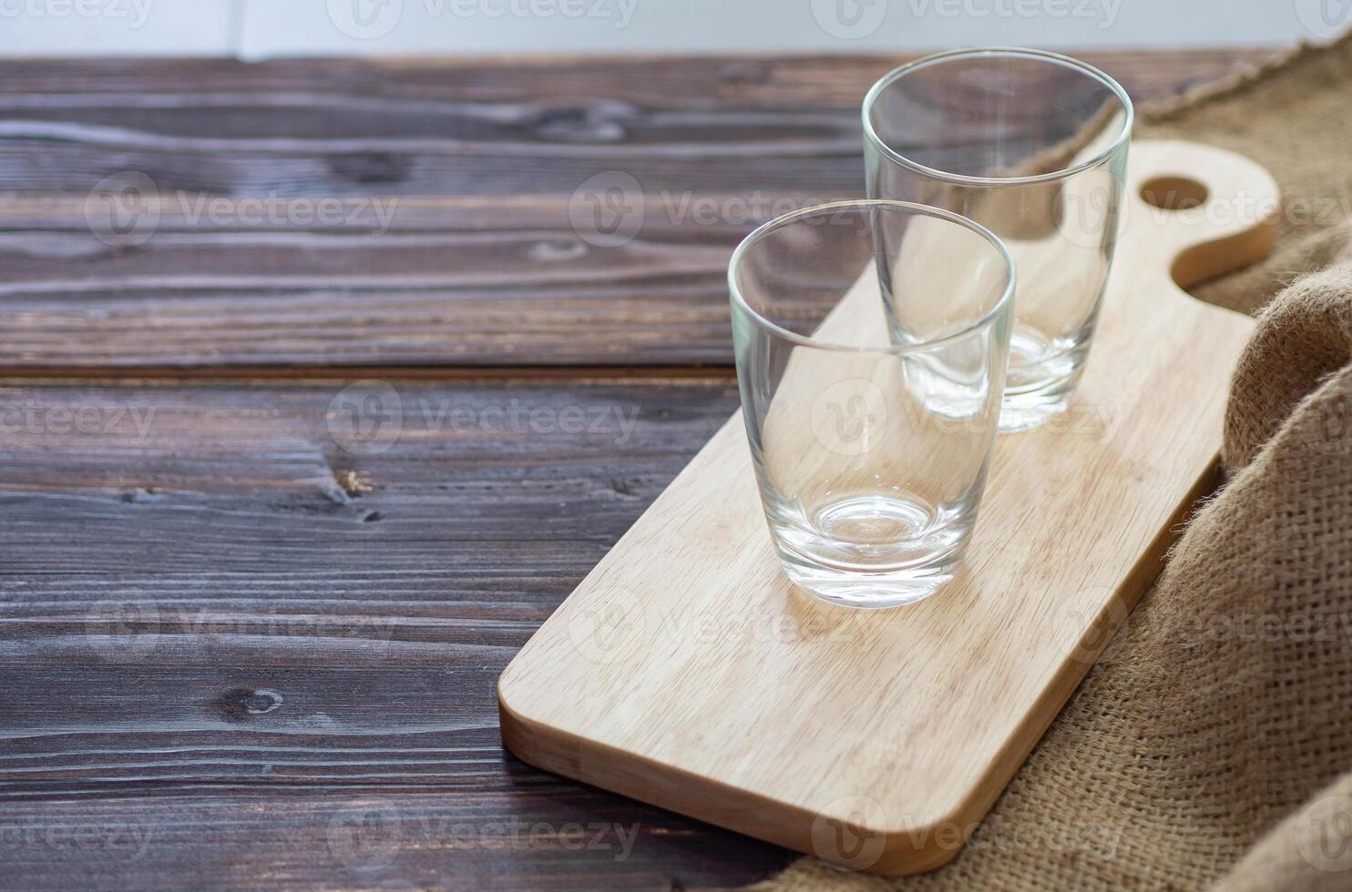 lato Visualizza di Due vuoto bicchieri su piccolo di legno taglio tavola posto vicino Marrone tela di sacco su Marrone di legno tavolo. bicchieri tazza per bevande. bevanda concetto foto