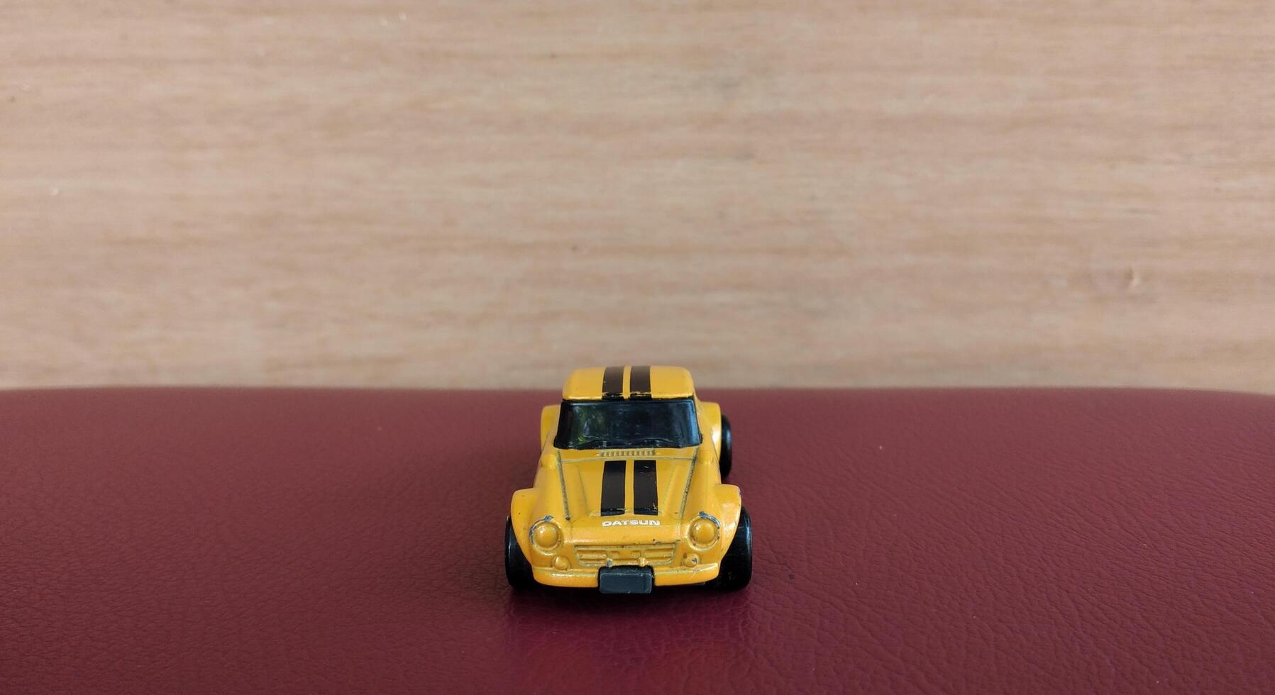 miniatura giallo auto giocattolo su rosso sfondo con copia spazio per testo foto