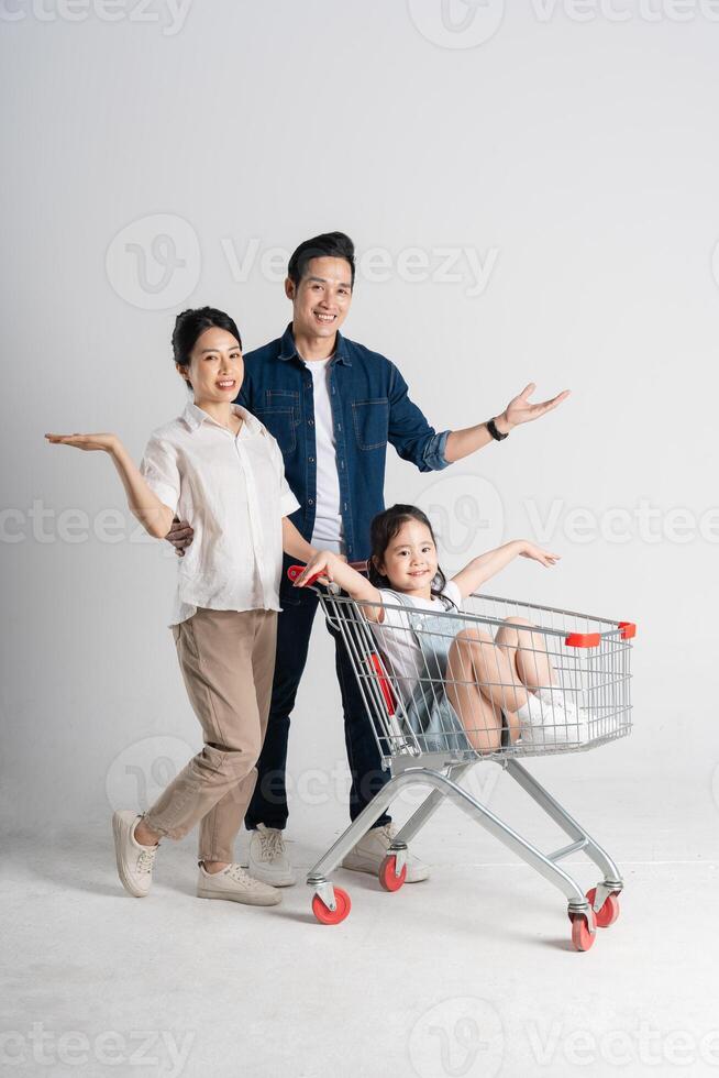 Immagine di asiatico famiglia spingendo un' supermercato carrello mentre acquisti, isolato su bianca sfondo foto
