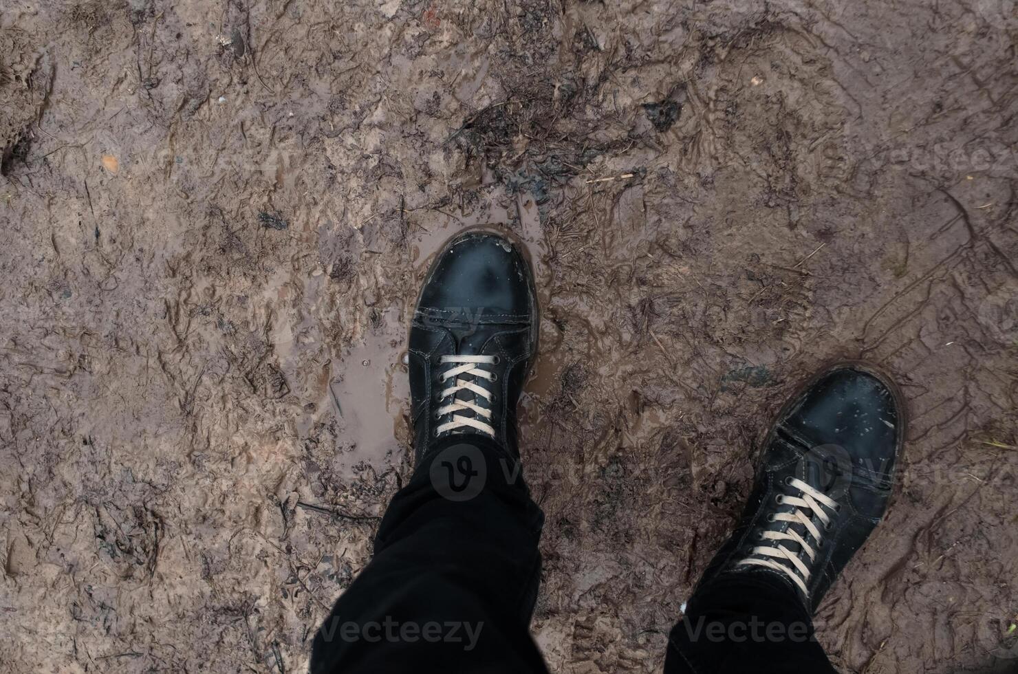 stivali in piedi nel fango e fanghiglia, pov. concetto cattivo tempo atmosferico, fuori strada, scongelare foto
