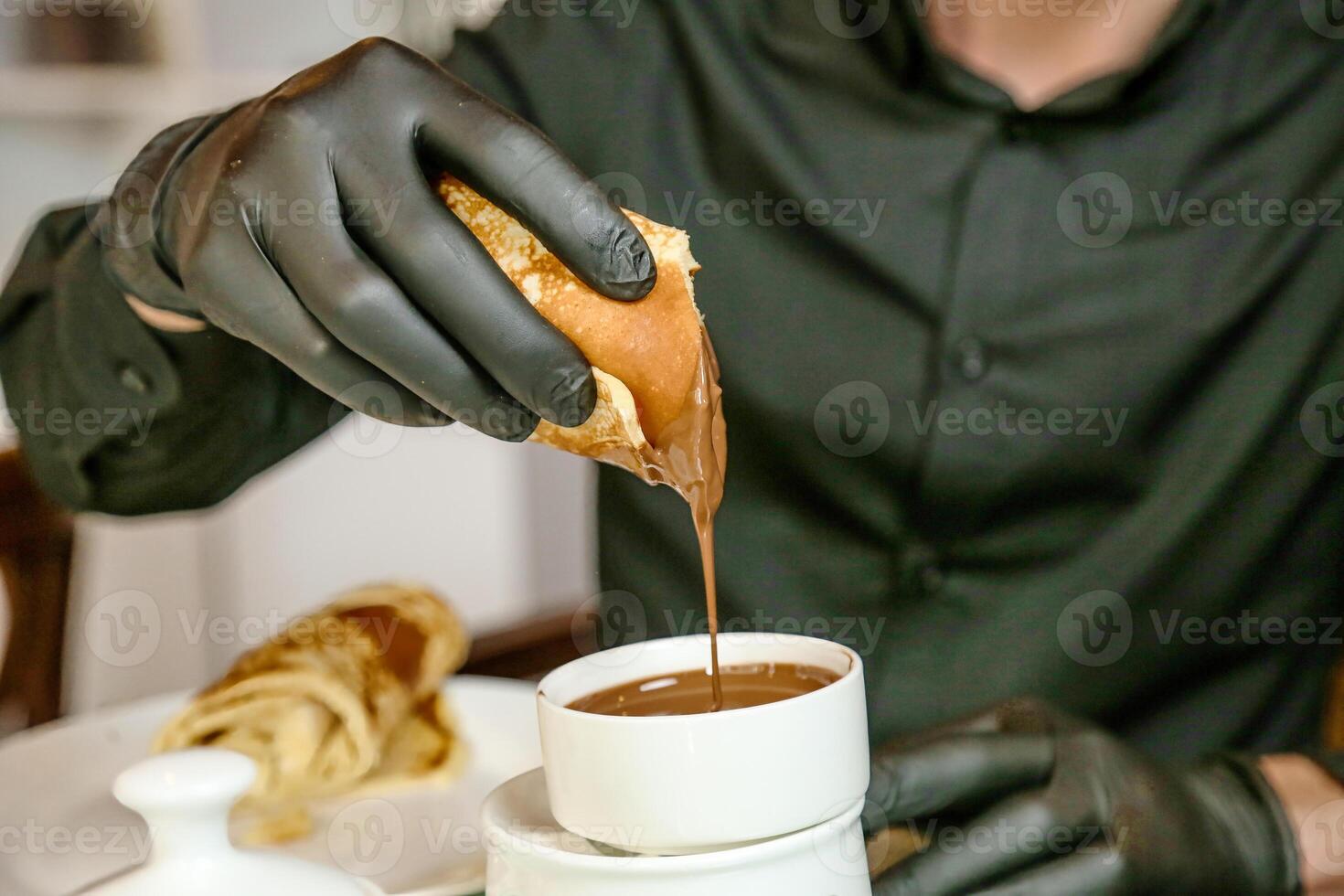 persona nel nero guanti tuffi oggetto in tazza foto