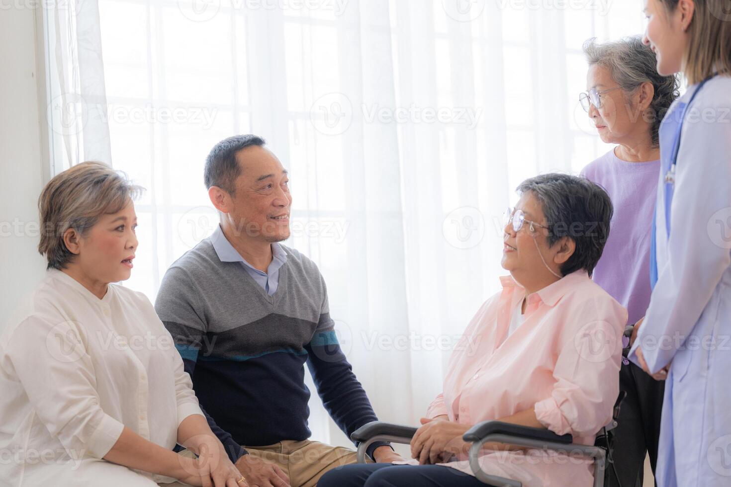 asiatico giovane infermiera supporto coppia anziano più vecchio donna nel un' sedia a rotelle. anziano maturo e un' gruppo di anziano amici vivente nel il Ospedale. socializzazione di pensionato le persone. foto