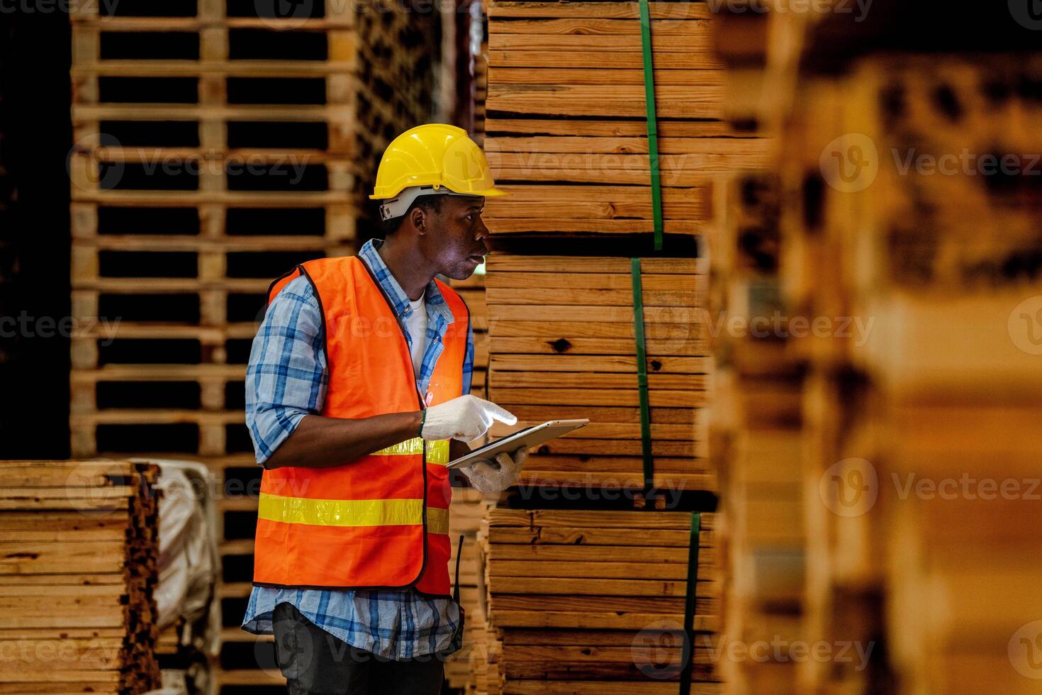 africano lavoratore falegname indossare sicurezza uniforme e difficile cappello Lavorando e controllo il qualità di di legno prodotti a laboratorio produzione. uomo e donna lavoratori legna nel buio magazzino industria. foto