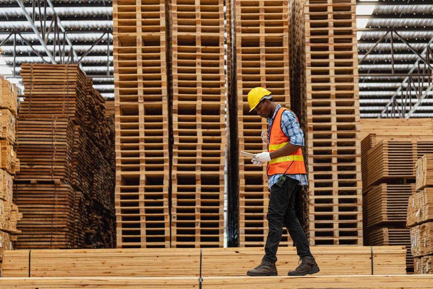 africano lavoratori uomo ingegneria a piedi e ispezionando con Lavorando suite vestito e mano guanto nel legname legna magazzino. concetto di inteligente industria lavoratore operativo. legna fabbriche produrre legna palato. foto