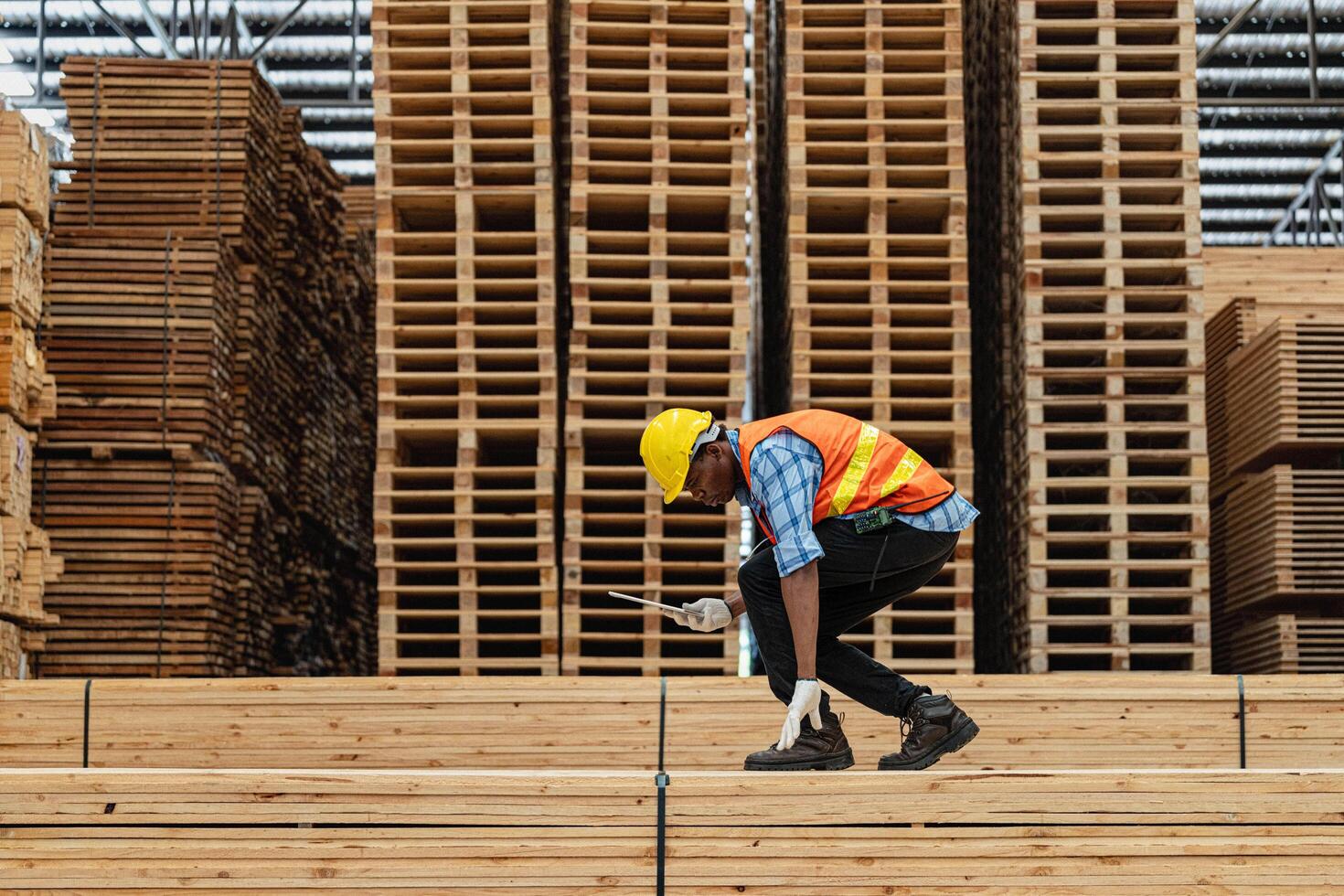 africano lavoratori uomo ingegneria a piedi e ispezionando con Lavorando suite vestito e mano guanto nel legname legna magazzino. concetto di inteligente industria lavoratore operativo. legna fabbriche produrre legna palato. foto