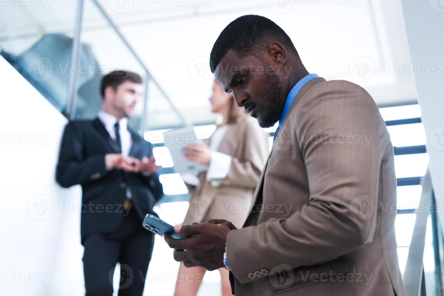 inteligente nero uomo d'affari Guardando mobile Telefono. Calvo adulto uomo indossare formale indossare. riflessivo afroamericano uomo d'affari nel un' perfettamente su misura completo da uomo in piedi nel scala nel ufficio. foto