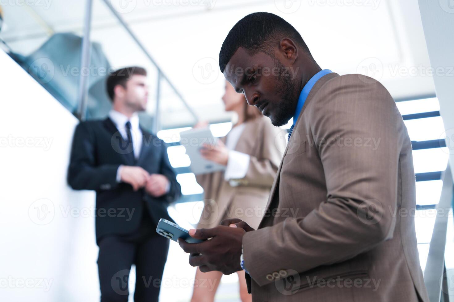 inteligente nero uomo d'affari Guardando mobile Telefono. Calvo adulto uomo indossare formale indossare. riflessivo afroamericano uomo d'affari nel un' perfettamente su misura completo da uomo in piedi nel scala nel ufficio. foto