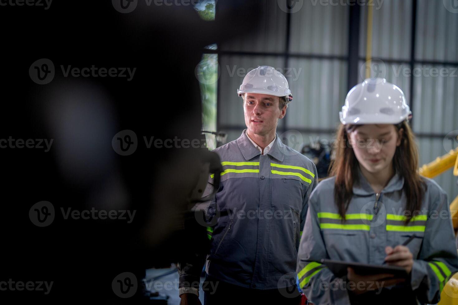 fabbrica ingegnere donna ispezionando su macchina con inteligente tavoletta. lavoratore lavori a macchina robot braccio. il saldatura macchina con un' a distanza sistema nel un industriale fabbrica. artificiale intelligenza concetto. foto