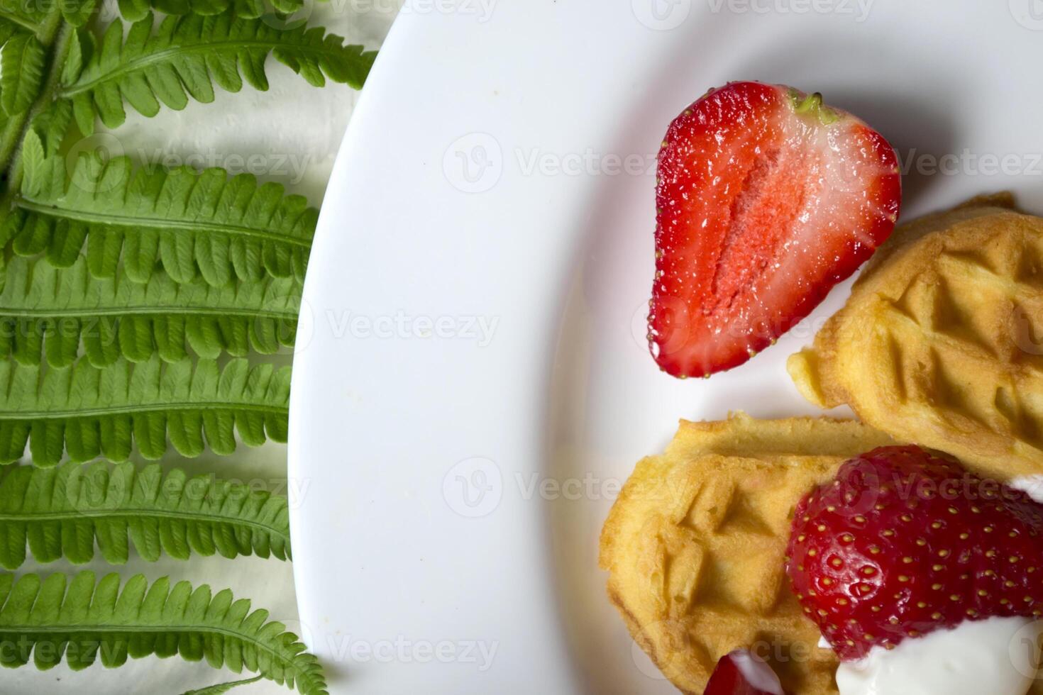 cialde con fragola su un' piatto, verde le foglie di felce su un' tavolo. vicino su. bellissimo e gustoso prima colazione. foto