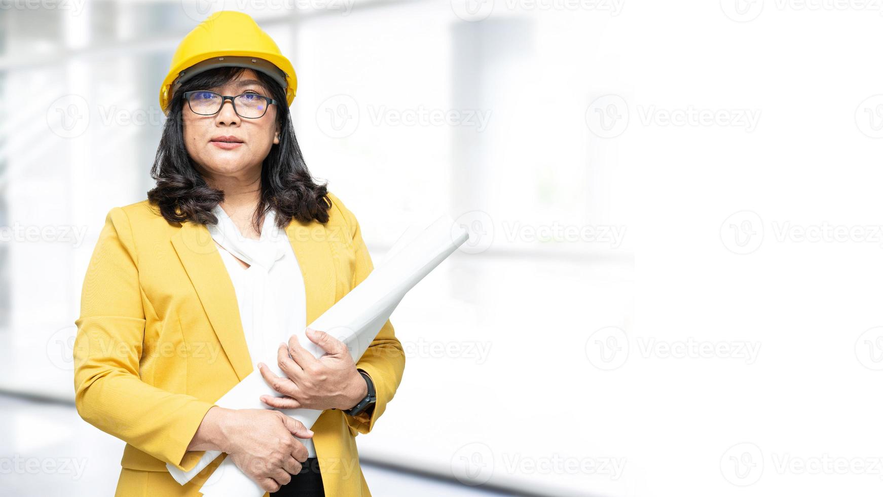 donna asiatica dell'ingegnere che sta al fondo dell'ufficio con lo spazio della copia, la costruzione di ingegneria e il concetto di architettura. foto