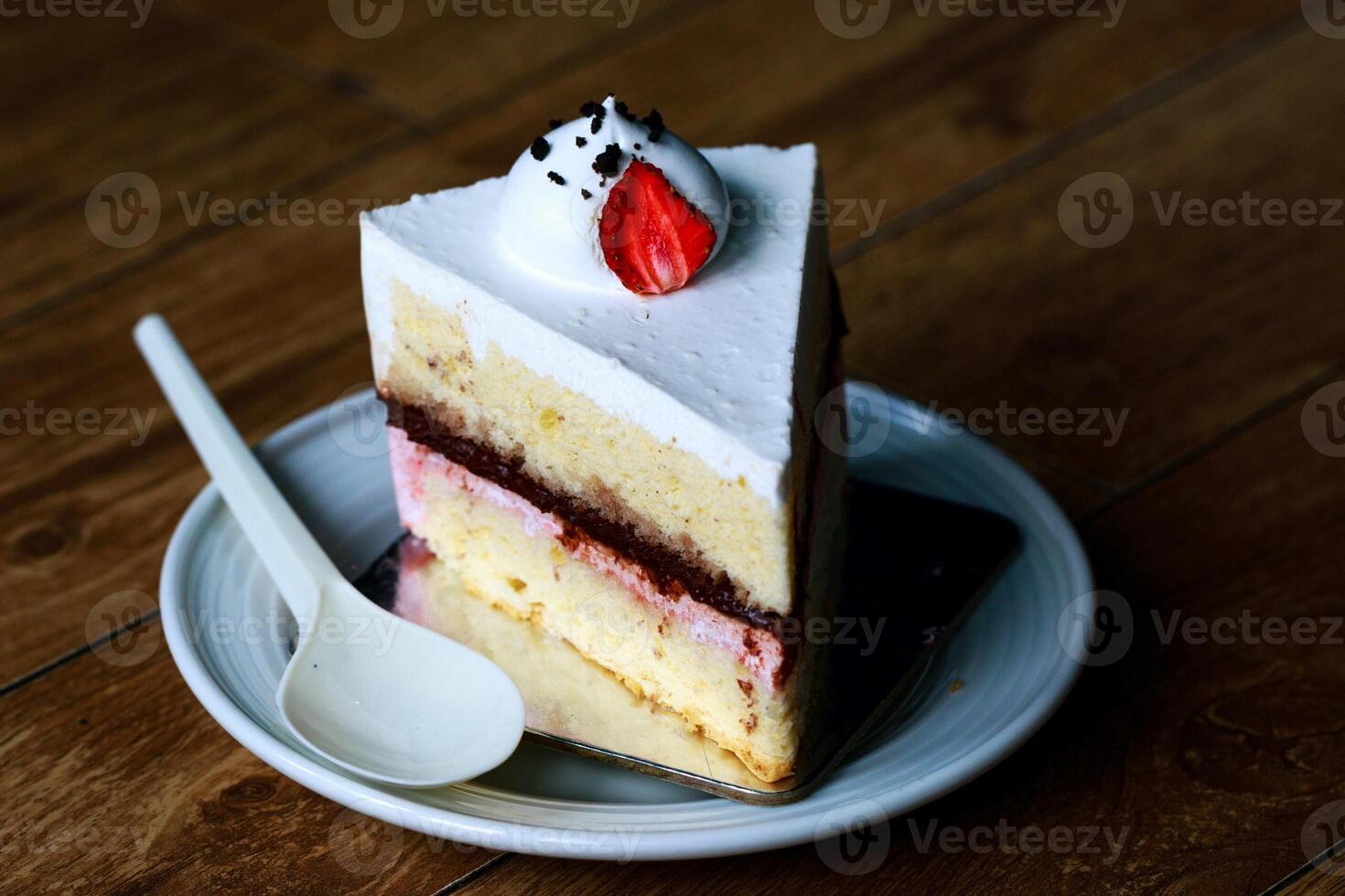 fragola torta su bianca piatto con cucchiaio su di legno tavolo. foto
