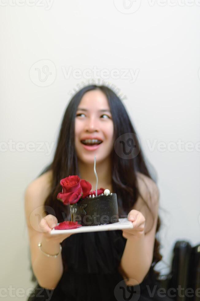 bellissimo donna indossare un' nero vestito e cioccolato torta nel il concetto di compleanno foto