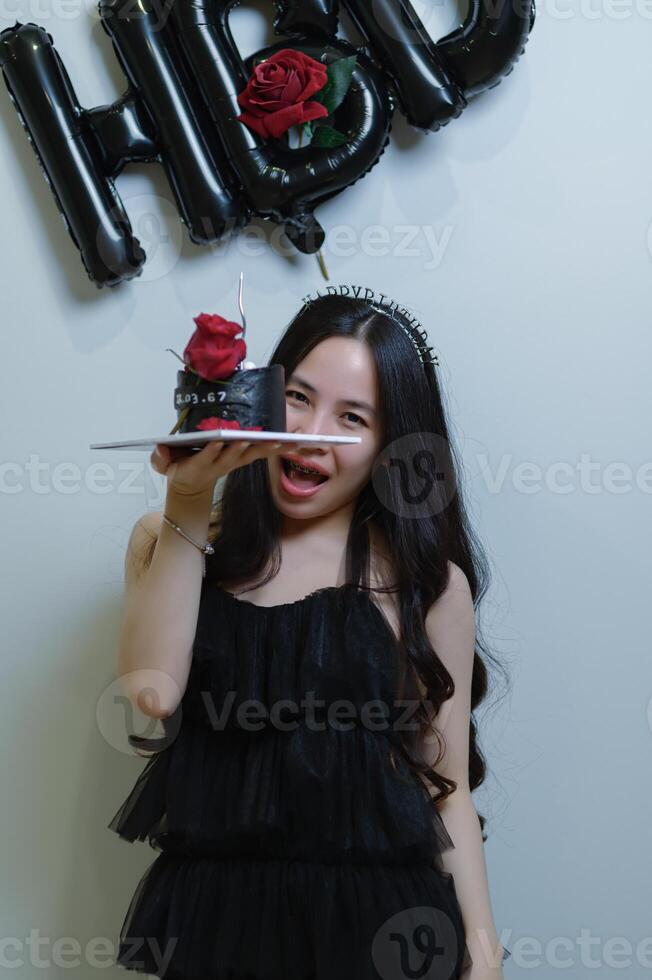 bellissimo donna indossare un' nero vestito e cioccolato torta nel il concetto di compleanno foto